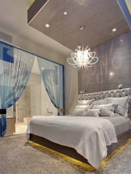 спальня відділена шторами від кімнати, над ліжком люстра цікавої форми