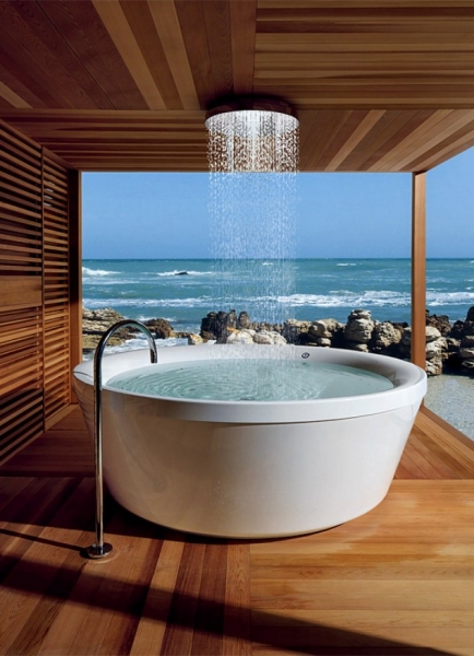 вода падає з великого душу в стелі на ванну з виглядом на океан